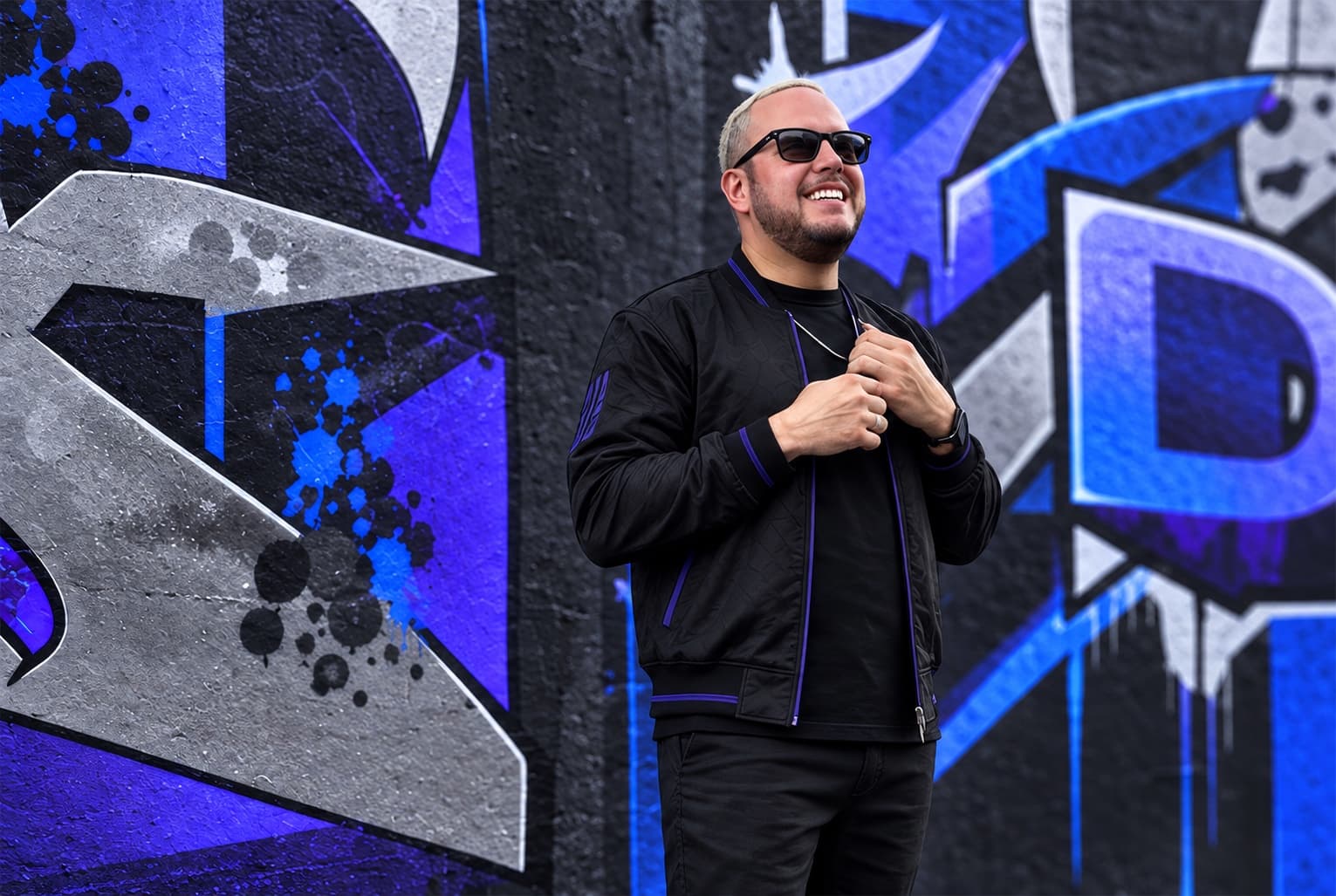 DJ Sojo in front of a blue and indigo mural